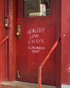 a red door with graffiti written on it and a hand rail in front of it