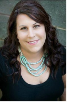 a woman with long dark hair wearing a black shirt and two necklaces on her neck