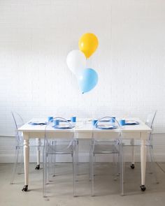 a white table topped with blue and yellow balloons