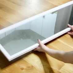 a person is holding the bottom part of a white cabinet with glass doors on it