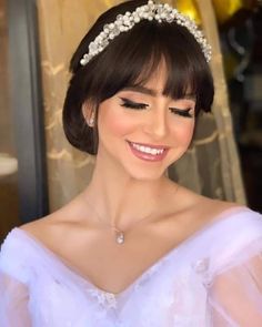 a woman wearing a tiara and smiling at the camera with her hair in a bun