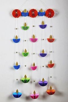 colorful paper fans are hanging on the wall next to a white wall with gold accents