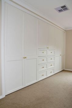 an empty room with white cabinets and beige carpet