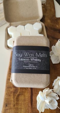 soy wax melts in a box with white flowers on the table next to it