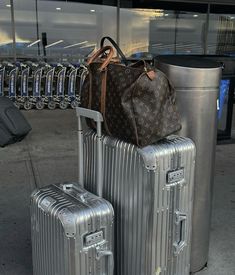 two pieces of luggage sitting on top of each other next to a metal trash can