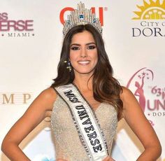 a woman wearing a tiara standing in front of a red carpet at an event