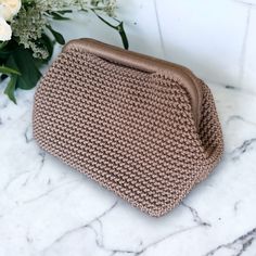 a brown purse sitting on top of a marble counter next to white flowers and greenery