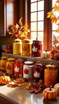 the kitchen counter is covered in autumn leaves and jars with maples on them, along with pumpkins