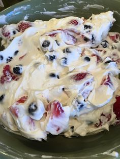 a green bowl filled with fruit and cream covered in icing on top of a table