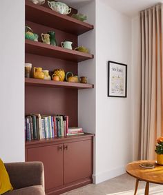 a living room filled with furniture and bookshelves next to a window covered in curtains