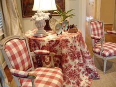 a dining room table covered in red and white checkered fabric with chairs around it