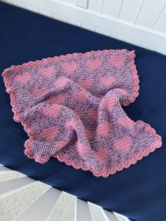 a crocheted blanket laying on top of a blue bed next to a white wall