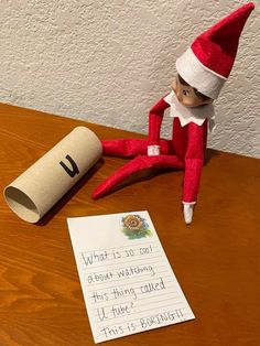 an elf is sitting on the table next to a roll of paper