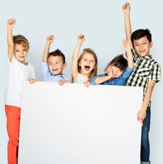 four children holding up a large white sign with their arms in the air and smiling