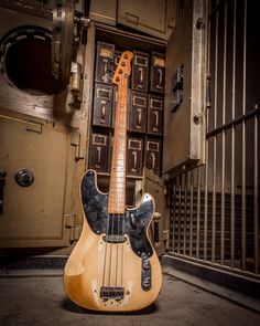 an old bass guitar sitting in front of a jail cell