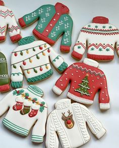 some decorated cookies are laying on a white tablecloth with christmas sweaters and mittens