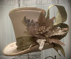 "This stunning gold and green tree topper top hat and/or centerpiece is READY TO SHIP. This top hat can be used as an elegant Christmas tree Topper or a Christmas decoration centerpiece. Made with ivory canvas fabric and decorated in ivory and gold.    Measures about 9.5\" tall (not including the picks) x 12\" at the brim Our top hat tree toppers/centerpieces are 100% handmade by us with high-quality materials. The designs are our own unique design. Our top hat tree toppers/centerpieces stand al Ivory Christmas Tree, Top Hat Centerpieces, Top Hat Tree Topper, Silver Tree Topper, Snowman Tree Topper, Peacock Christmas Tree, Gold Tree Topper, Art Hats, Gold Corset