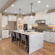 a large kitchen with white cabinets and wooden floors