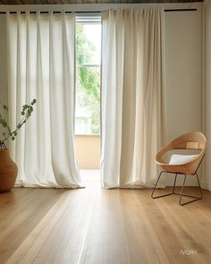 an empty room with white curtains and a chair in front of the window, next to a potted plant