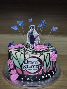 a decorated cake with an image of a demon slayer on the top and butterflies around it