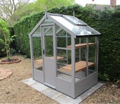 a small gray greenhouse in the middle of a garden