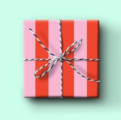 a pink and red striped gift box tied up with twine on mint green background