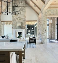 an open living room and dining area with stone walls, wood flooring and large windows