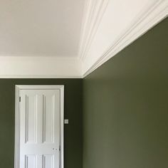 an empty room with a white door and green walls in the corner that is painted dark green