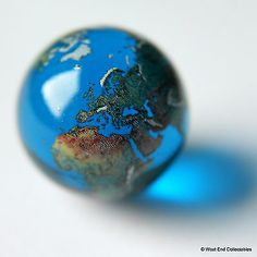 an image of a blue marble with the world in it's center on a white surface