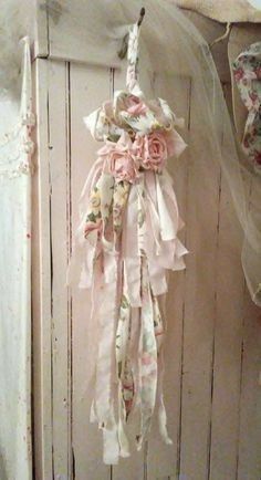 an old door is decorated with pink flowers and ribbons hanging from it's side