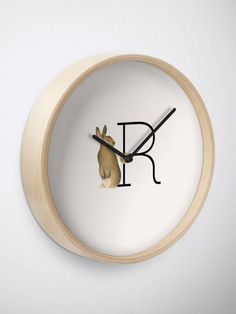 a clock with the letter r on it's face and a rabbit peeking out from behind