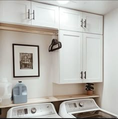 a washer and dryer in a small room with white cabinets on the wall