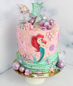 a pink and blue cake with mermaid decorations