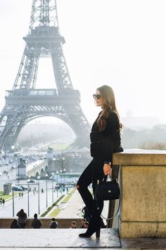 a woman standing in front of the eiffel tower with her hand on her hip