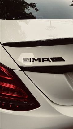 the back end of a white car with an amg emblem on it's side