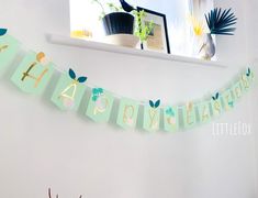 a happy birthday banner hanging on the wall in a room next to a potted plant