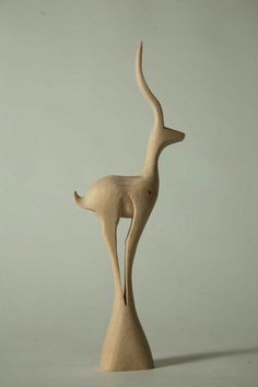 a wooden sculpture of a bird on a white surface with a gray wall in the background