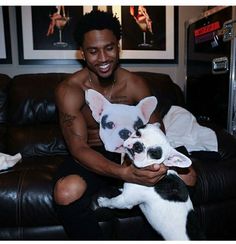 a man sitting on a couch holding a small white and black dog in his lap