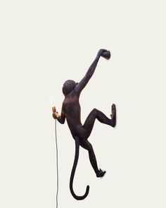 a statue of a monkey holding a light bulb in it's right hand while standing on its hind legs