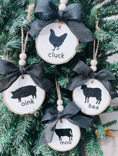 three ornaments hanging from a christmas tree decorated with black and white farm animals on them