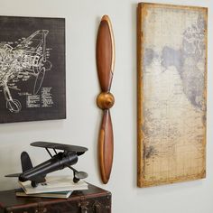 an airplane propeller mounted on the wall next to a map and other art pieces in a living room