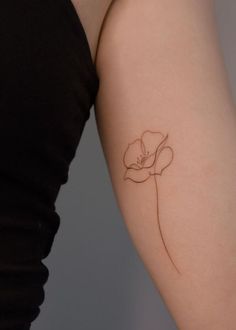 a woman's arm with a single flower tattoo on the left side of her arm