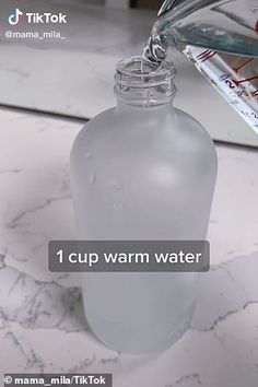 a person pouring water into a glass bottle on top of a marble counter with the words 1 cup warm water