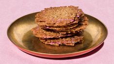 some cookies are on a gold plate with pink paper in the backgroung