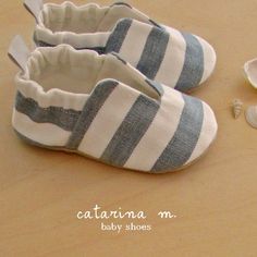 a pair of baby shoes sitting on top of a wooden table next to seashells