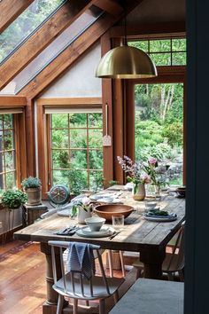 a dining room table with plates and cups on it, in front of large windows