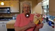 an elderly woman holding a box of cookies in her kitchen