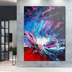 an abstract painting hangs on the wall next to a chair