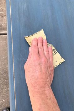 a person's hand on top of a piece of blue luggage with yellow adhesive tape