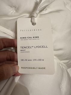 a person holding onto a white label that says, kingcal king tencel'n lyocell